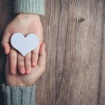 Close up 2 tangan sedang berpegangan di atas meja.