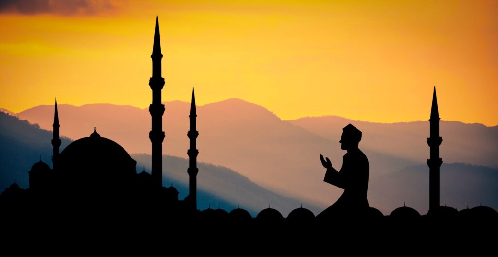 Seorang umat muslim sedang berdoa di samping masjid saat matahari terbenam